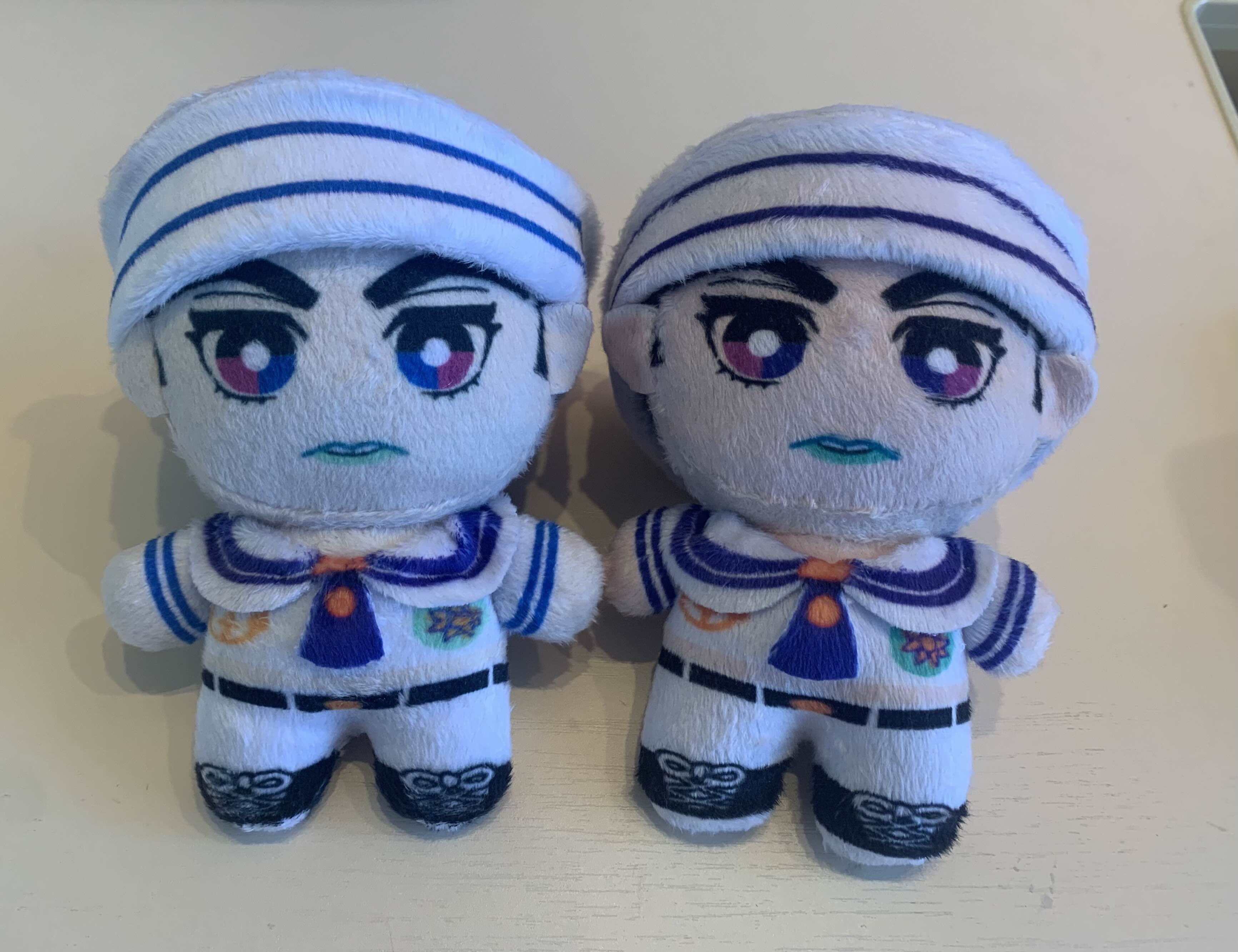 Two plush toys dressed in sailor outfits on a light surface.