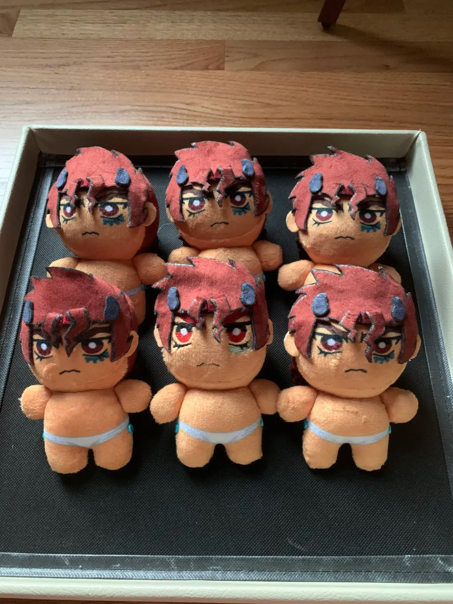 Five identical plush toys with red hair and angry expressions on a black tray.