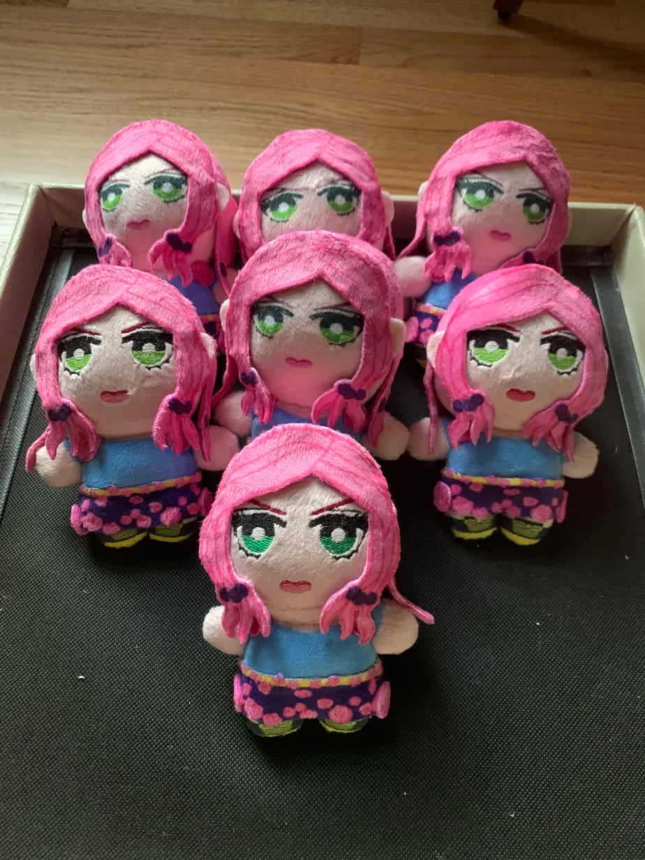 Set of plush toys with pink hair and green eyes on a black surface.