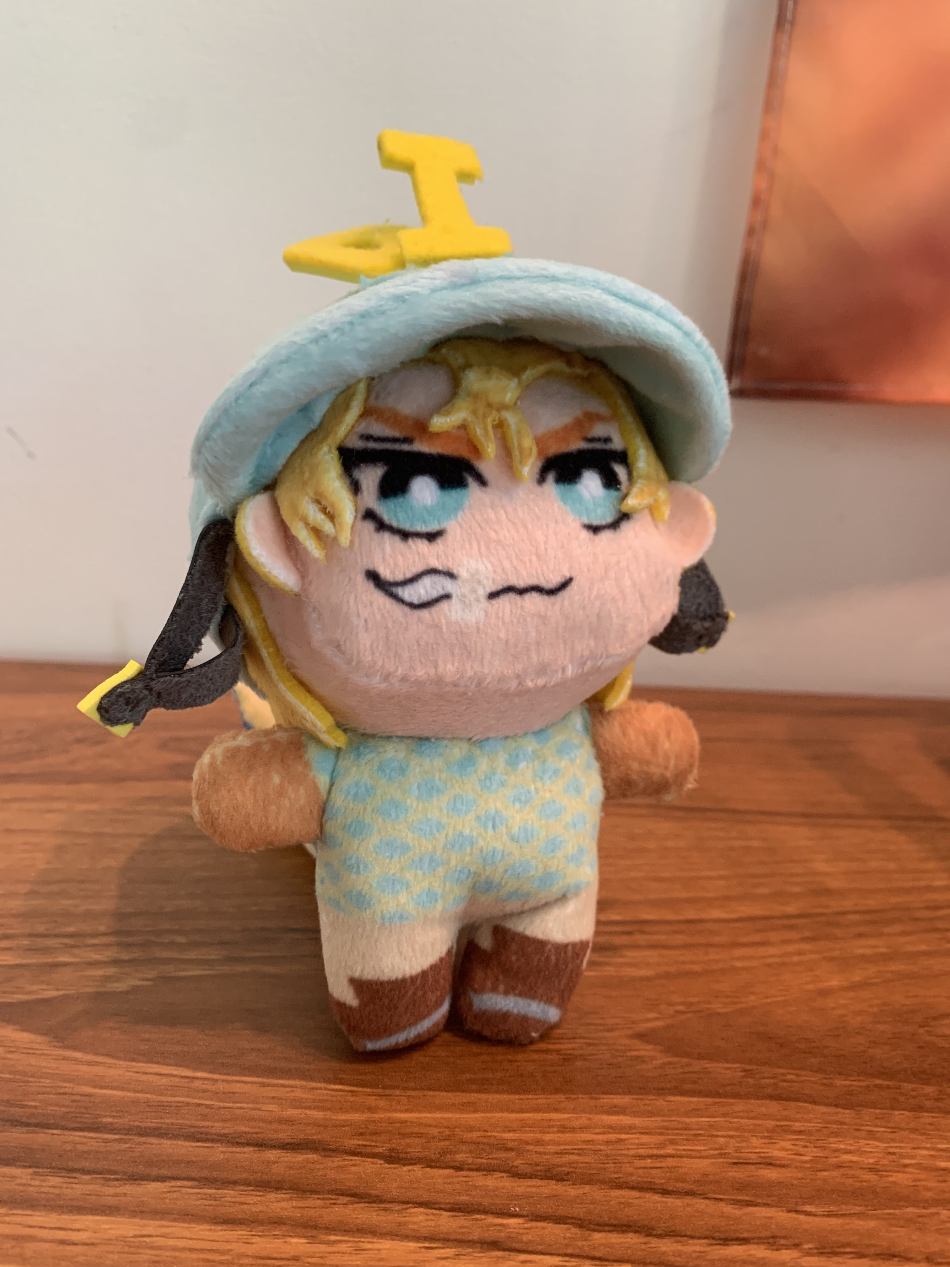 Plush toy with a blue jockey's cap standing up on a wooden surface