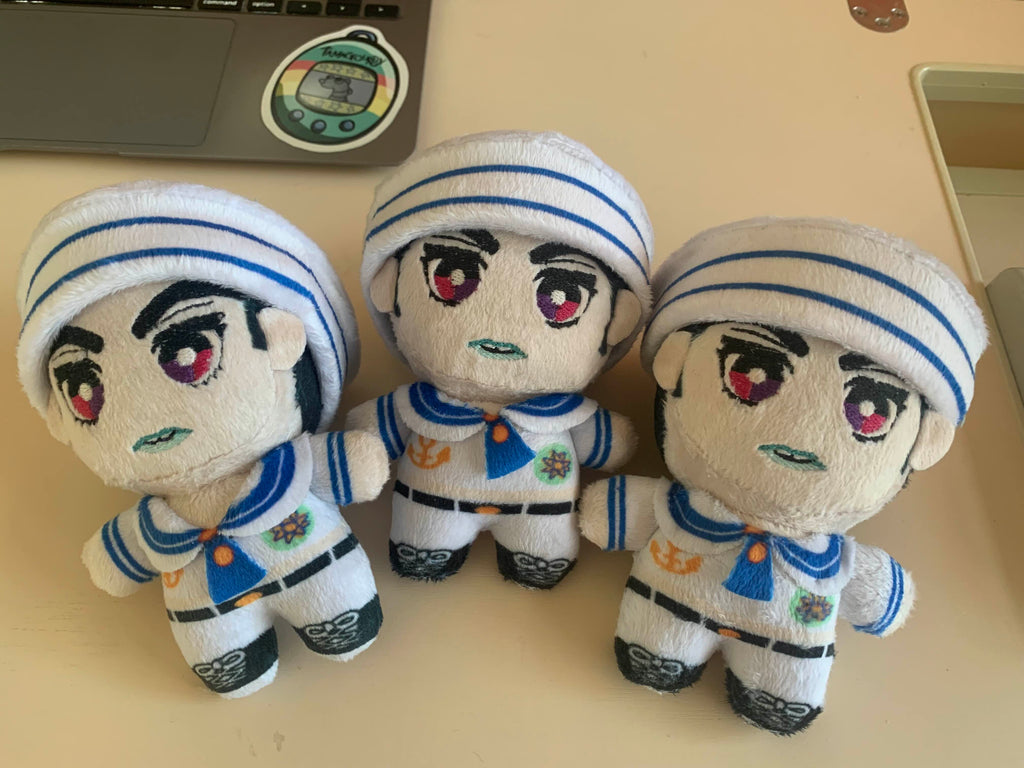 Three plush toys in sailor uniforms on a desk.
