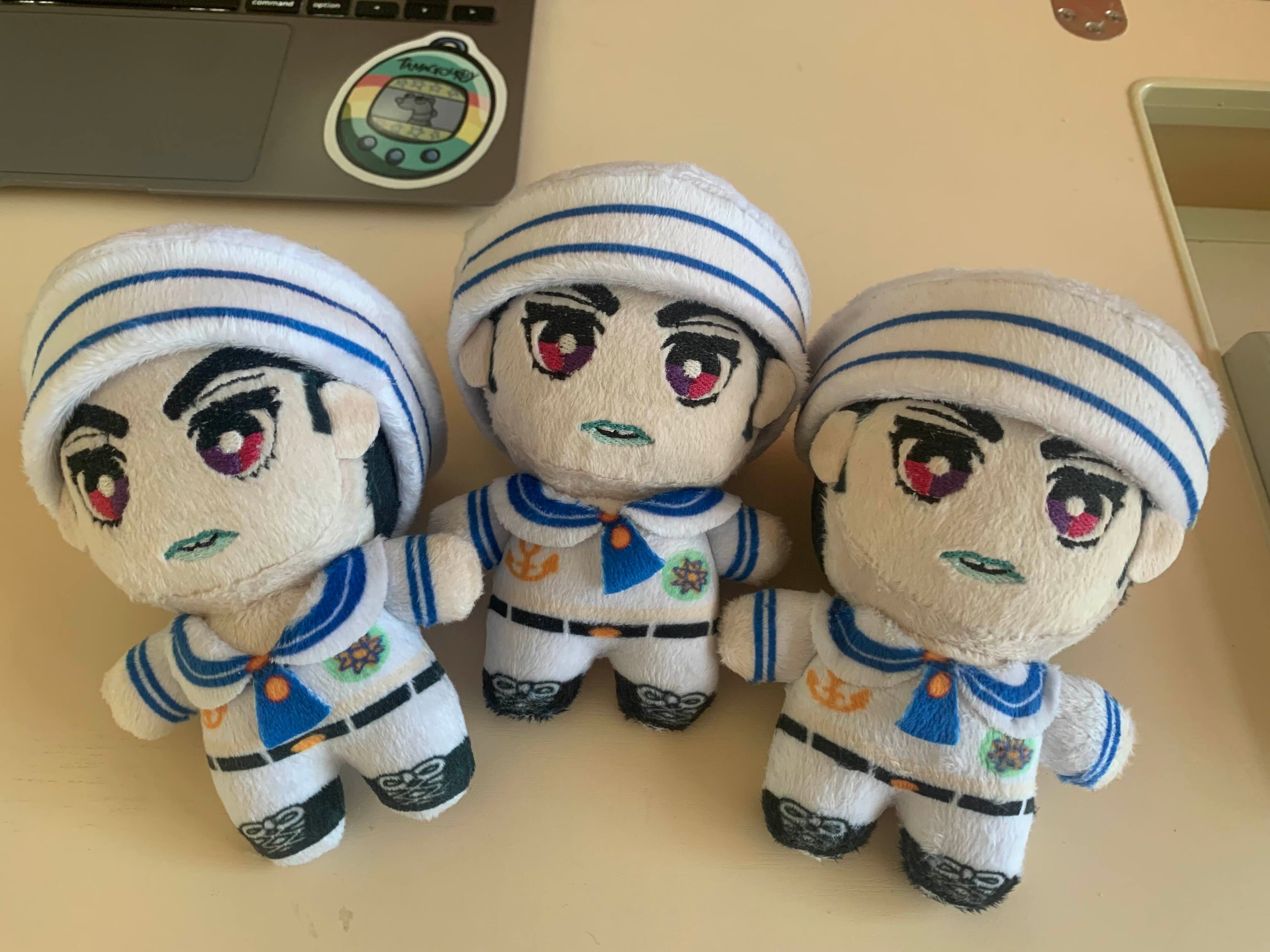 Three plush toys in sailor uniforms on a desk.