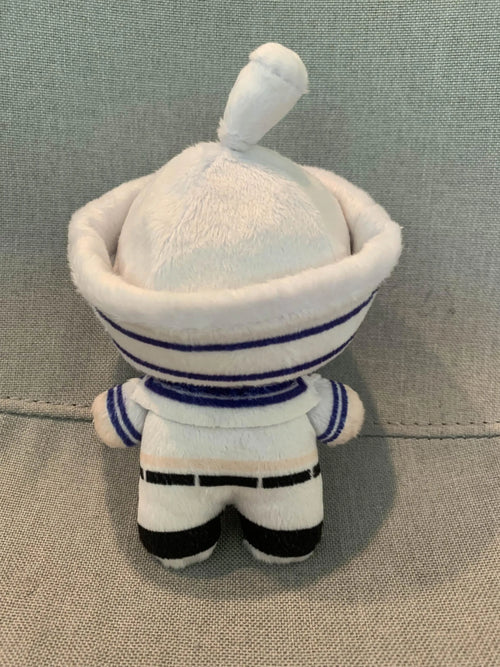 The back of a small plush toy in a sailor outfit on a gray background