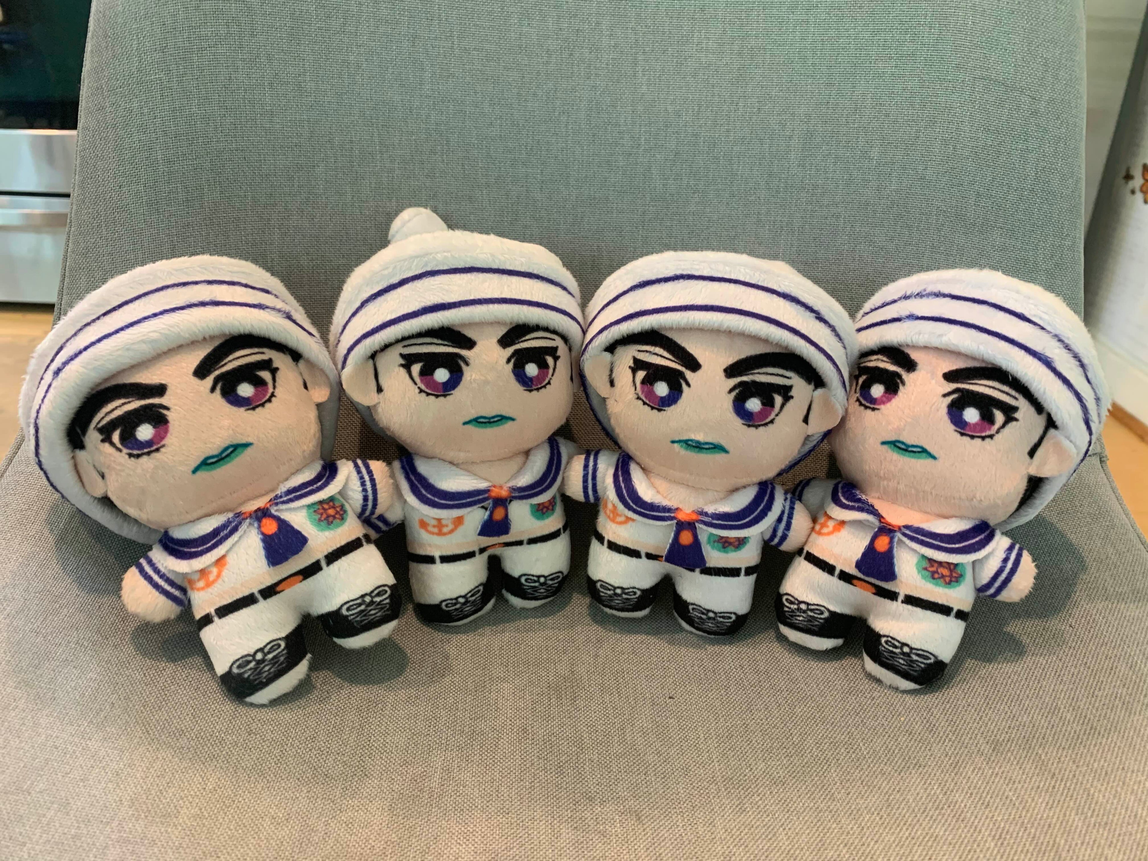 Four plush toys in sailor outfits on a grey background.