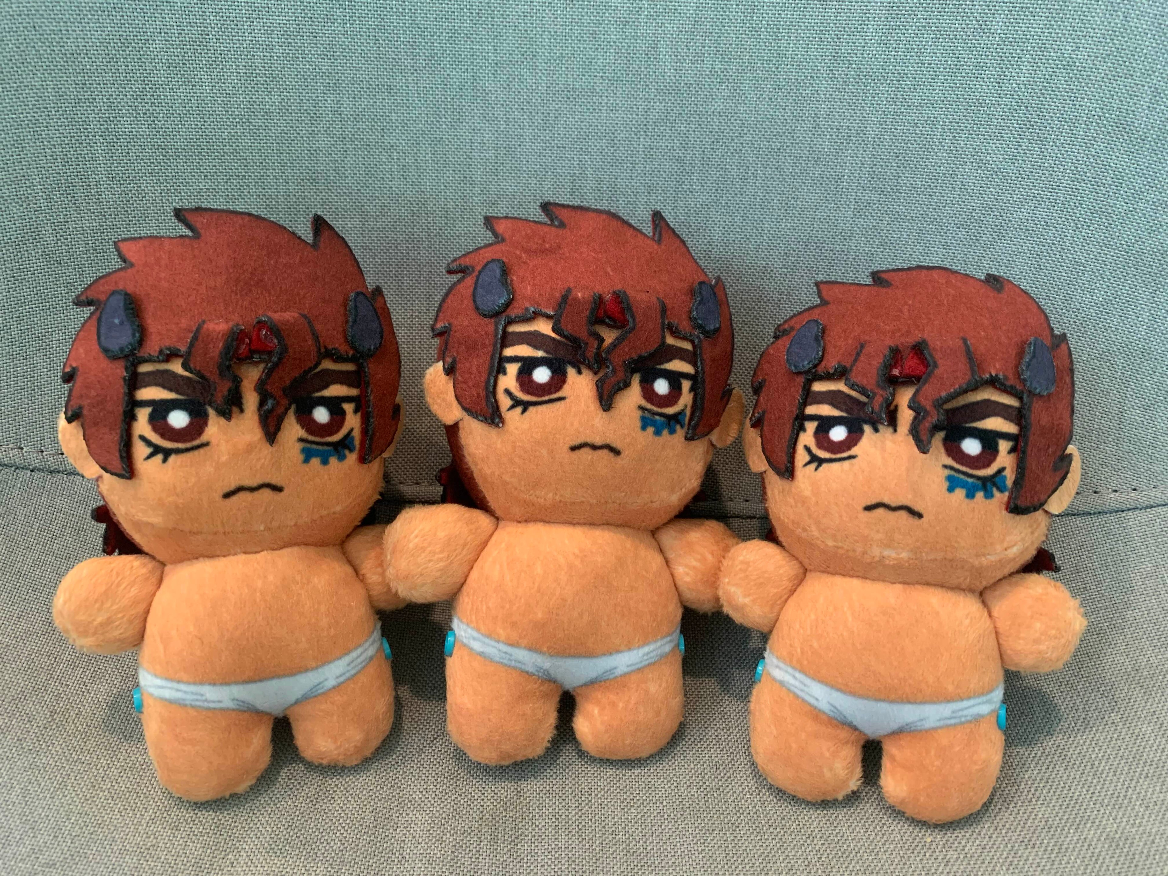Three plush toys with red hair and angry frowns on a grey background