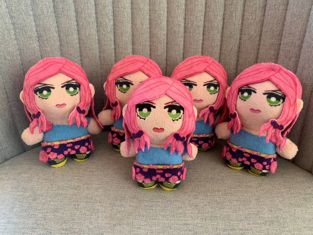 Five identical plush toys with pink hair and green eyes sitting on a gray surface.